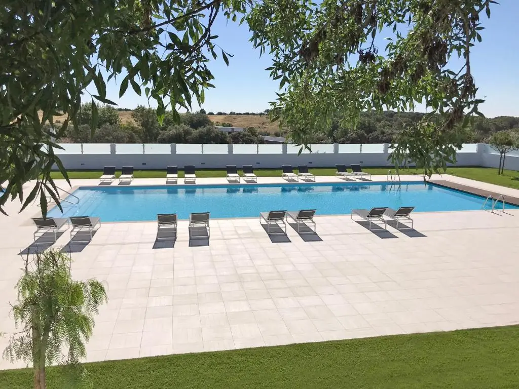 Piscina exterior com espreguiçadeiras e vista de jardim no Varchotel