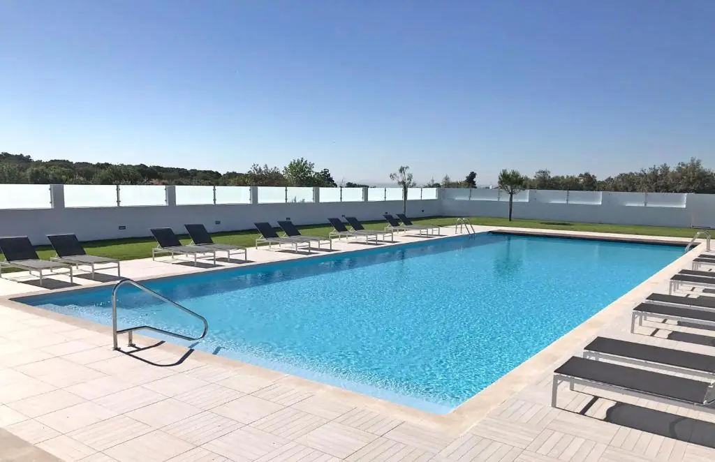 Piscina exterior com espreguiçadeiras no Varchotel